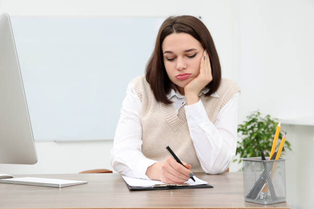 istock Puzzled young intern writing at table in modern office. First work day 1810301381