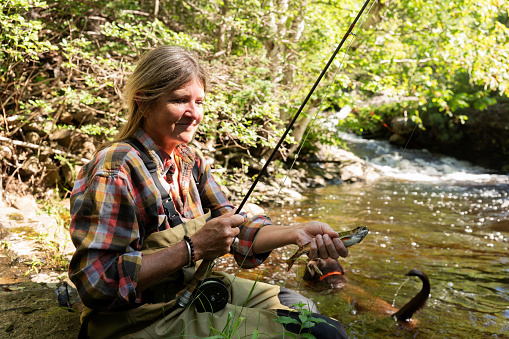 A mature woman fly-fishing for native brook trout.