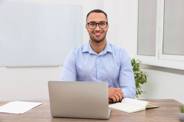 istock Happy young intern working with laptop at table in modern office 1810305860