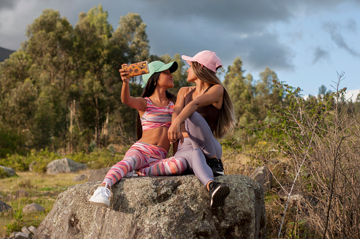 Mother and daughter enjoying motherhood taking a selfie with the cell phone on a rock outdoors. High quality photo