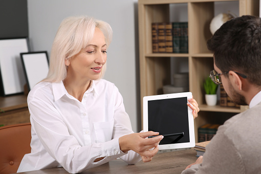 Boss pointing at tablet while discussing work issues with employee in office