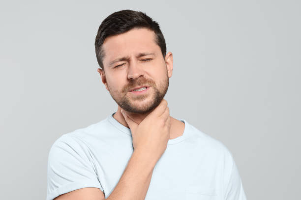 istock Man suffering from sore throat on light gray background 1810323239