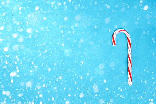 Candy cane Christmas decor with copy space. Blue background and snow.