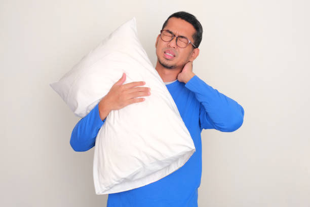 istock Adult Asian man suffering back neck pain while holding a sleeping pillow 1810343108