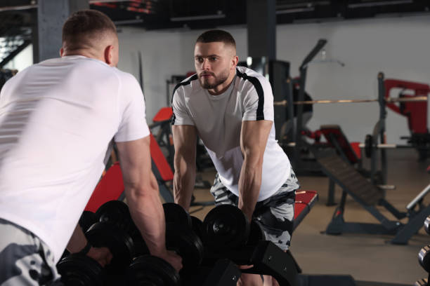 istock Man looking at mirror near dumbbells rack in gym 1810394176
