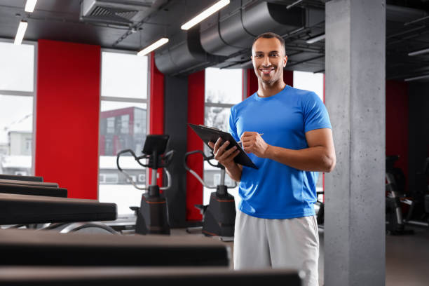 istock Happy trainer writing down workout plan in modern gym, space for text 1810395767