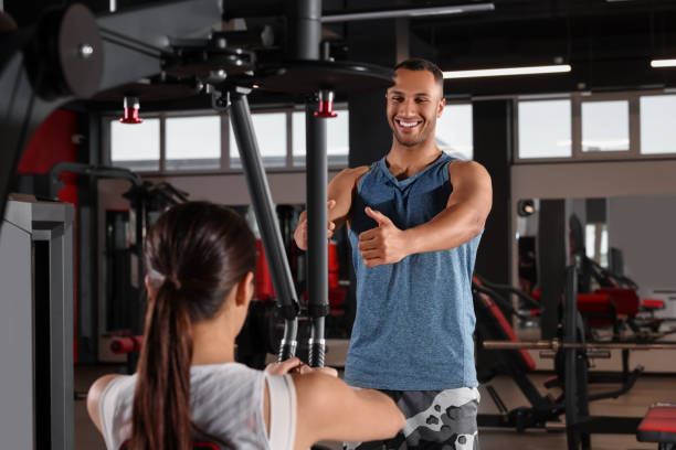 istock Happy trainer explaining woman how to do exercise properly in modern gym 1810395779
