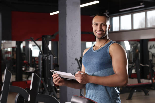 istock Happy trainer with workout plan in modern gym, space for text 1810396303