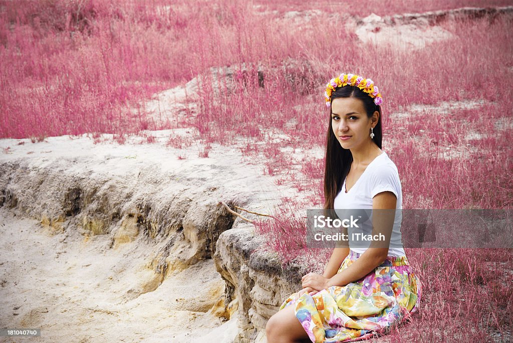 Belle jeune fille est assise près de fleurs roses field - Photo de Adulte libre de droits