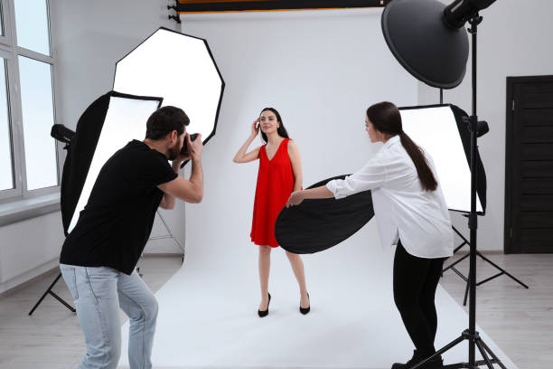 istock Professional photographer and assistant working with beautiful model in modern photo studio 1810421888
