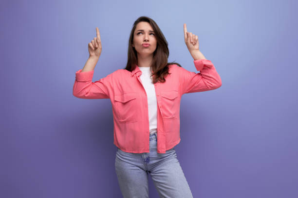istock focused black haired lady in casual style pointing thumb up at mockup space on studio background 1810432533