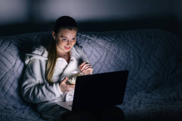 istock Young woman sitting on sofa at home, holding laptop computer on 1810437029