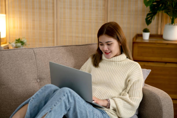 istock young woman is sitting comfortably on a sofa in a warm home  using a notebook 1810448784