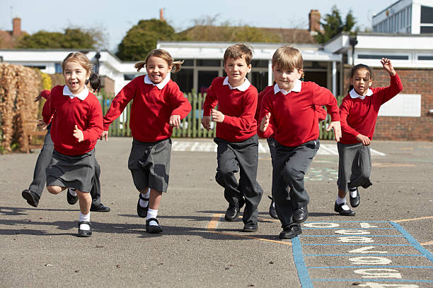 elementary school students running in playground - 制服 個照片及圖片檔