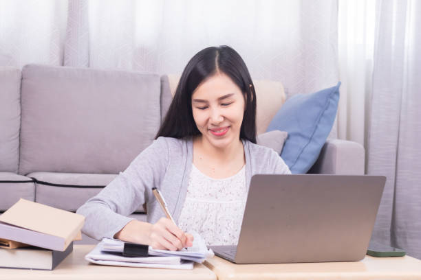 istock Asian happy female working at home calculate bookkeeping for tax declarations using modern technology laptop, well-organized planning financial payment for housing loan, women working paperwork bills 1810459143