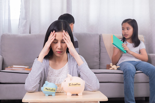 Asian stress headache mother worried to empty piggybank unsuccess to save money for medication and education for children, unsecured poor planning of single mom for finances bank and house expenses