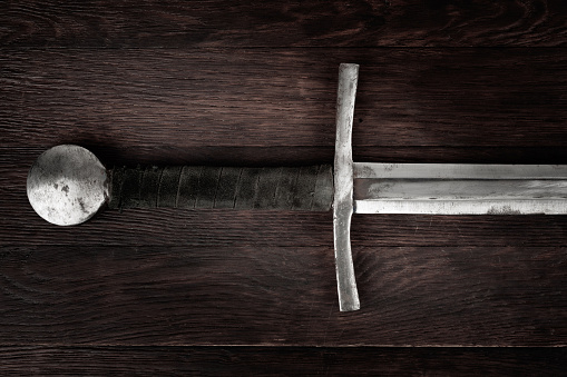 Medieval vintage sword on wooden background.