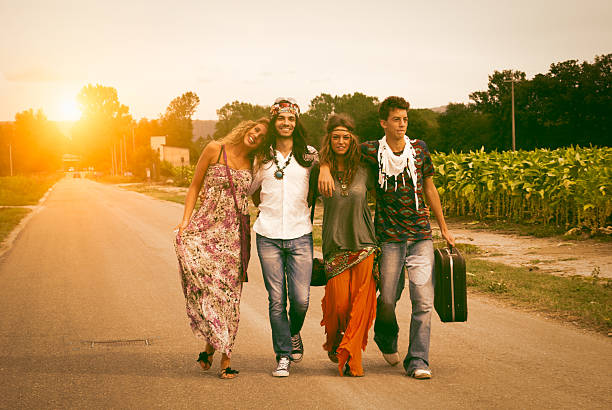 4 人の若い大人 hippie の友人を歩く田園地帯 - 1970s style hippie couple retro revival ストックフォトと画像