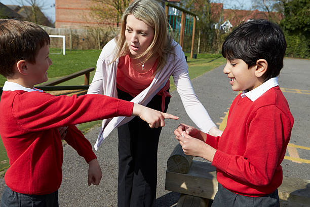 Teacher Stopping Two Boys Fighting In Playground Female Teacher Stopping Two Boys Fighting In Playground schoolyard fight stock pictures, royalty-free photos & images