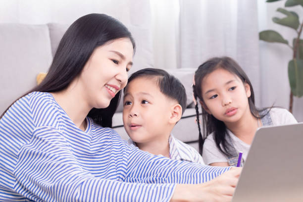 istock Asian mother teaching homework children at home using laptop technology support learning, kids boy and girl studying with nanny teacher have fun or watching video together relationship motherhood 1810469364