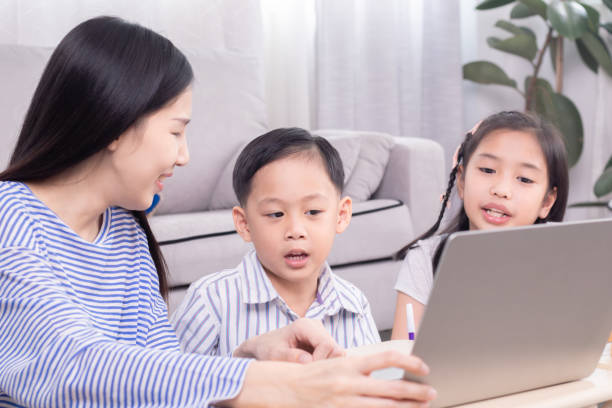 istock Asian mother teaching homework children at home using laptop technology support learning, kids boy and girl studying with nanny teacher have fun or watching video together relationship motherhood 1810469922