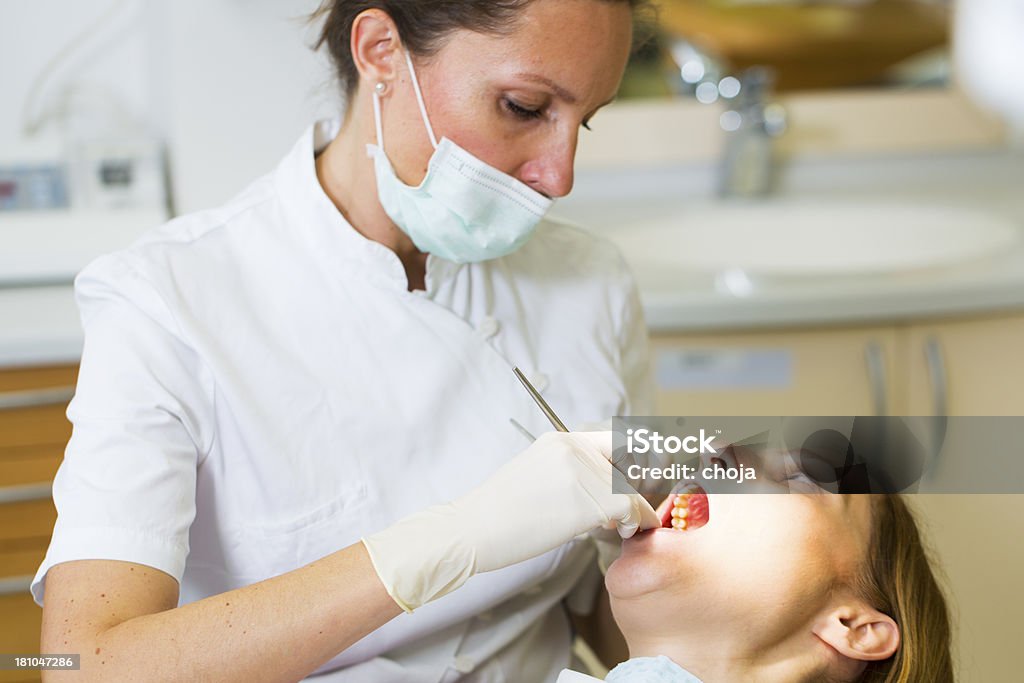 Dentista femmina in ufficio con donna paziente sulla sedia dentisti - Foto stock royalty-free di Adulto