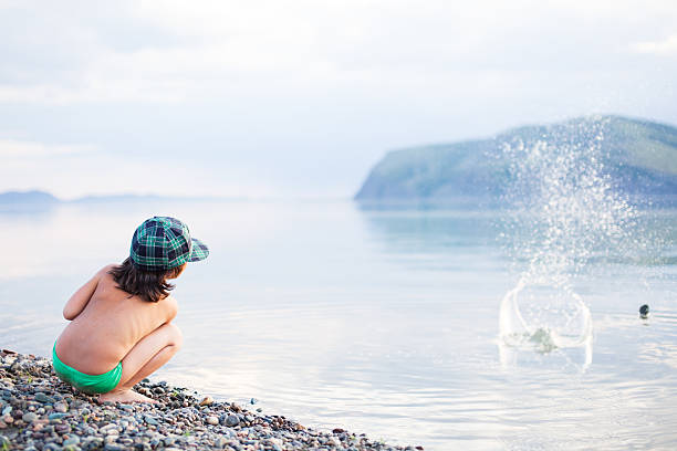 chłopiec bawi się z otoczaki na plaży - throwing stone little boys child zdjęcia i obrazy z banku zdjęć