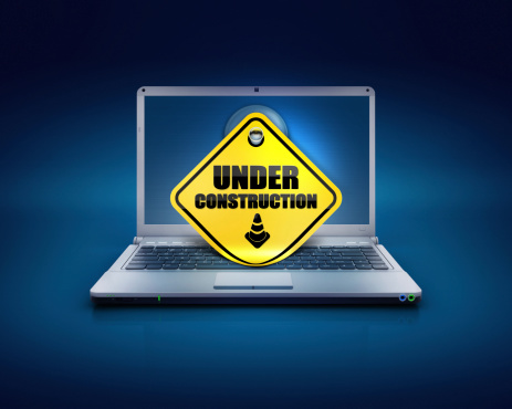 computer laptop on a blue background with sticky note showing the under construction words written on screen, Concept of website progress or web development or PC amendments.