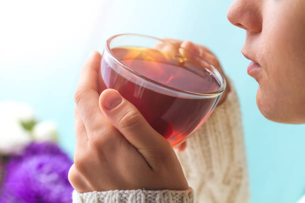 istock Woman in a warm, knitted, white pullover drinks black hot tea. Tea drinking. Comfort winter, warm autumn drinks. Cozy pastime 1810481428