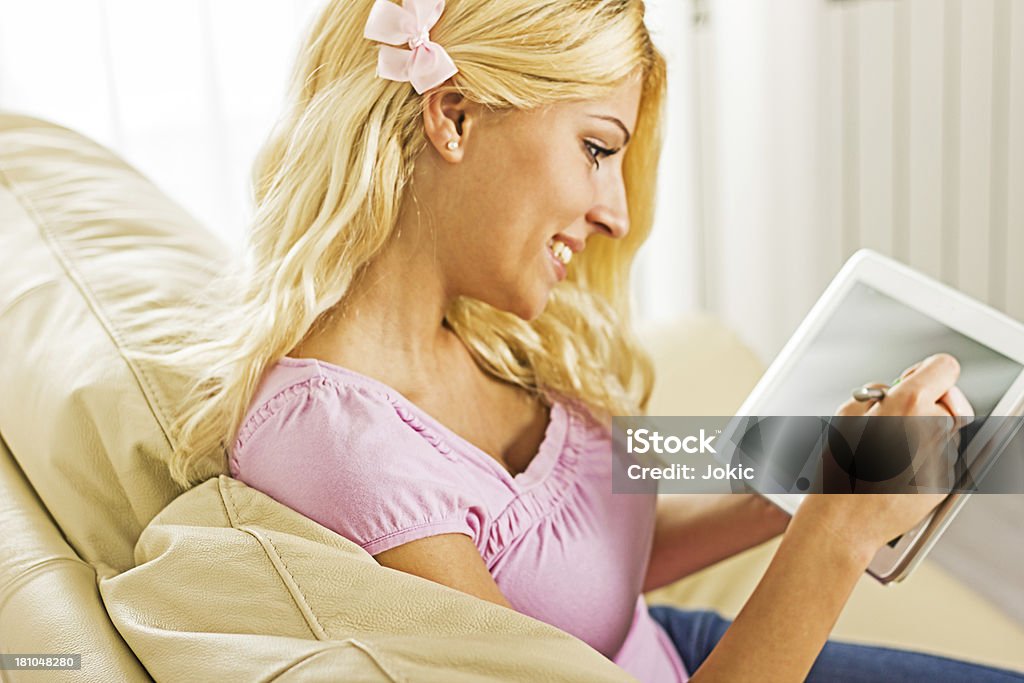 Mulher sorridente trabalhando em tablet em casa. - Foto de stock de 20 Anos royalty-free