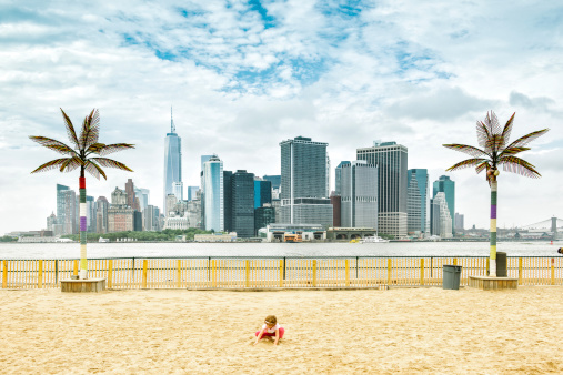 Little girl playing with the sand at Governors Island park beach. New York City. USA.