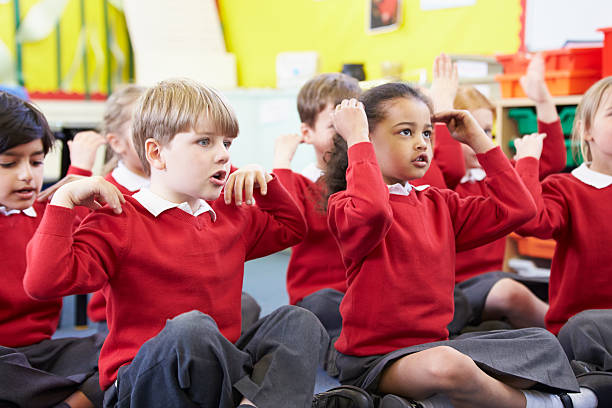 Pupils Perfoming Actions Whilst Singing Song Elementary Pupils Perfoming Actions Whilst Singing Song knee to the head pose stock pictures, royalty-free photos & images