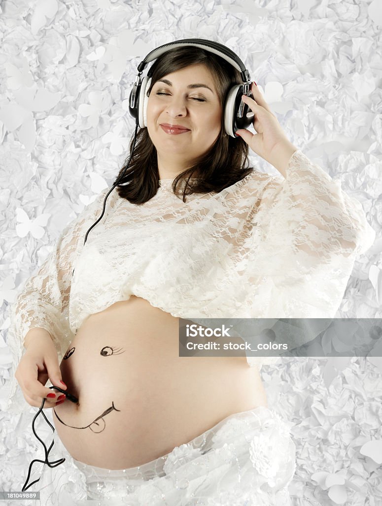 enjoying baby pregnant woman listening at headphones her baby. Abdomen Stock Photo