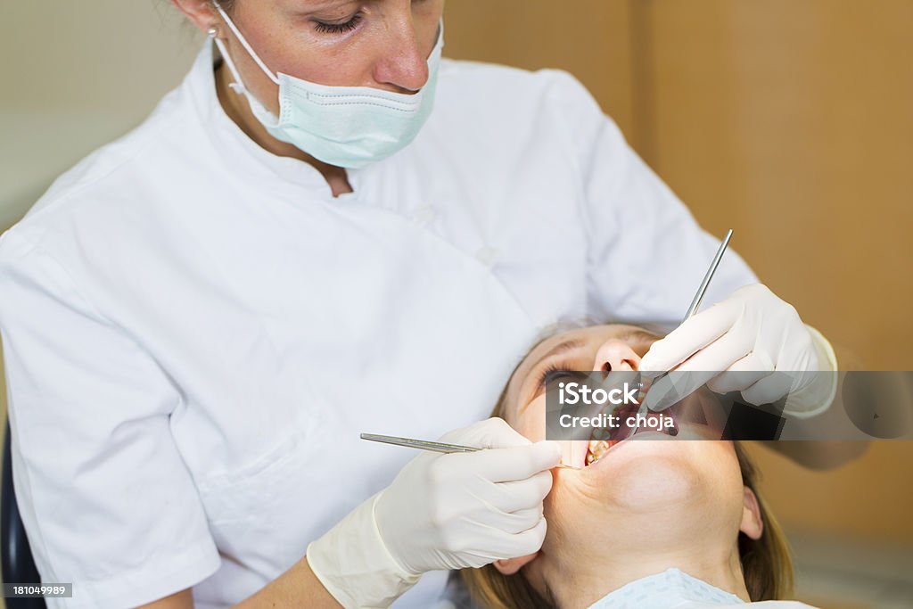 Dentista femmina in ufficio con donna paziente sulla sedia dentisti - Foto stock royalty-free di Adulto