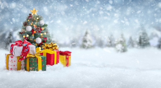 Blurred gift boxes and Christmas tree on abstract snow landscape background. Winter holiday sale concept. Panoramic banner with copy space. Soft focus on foreground.