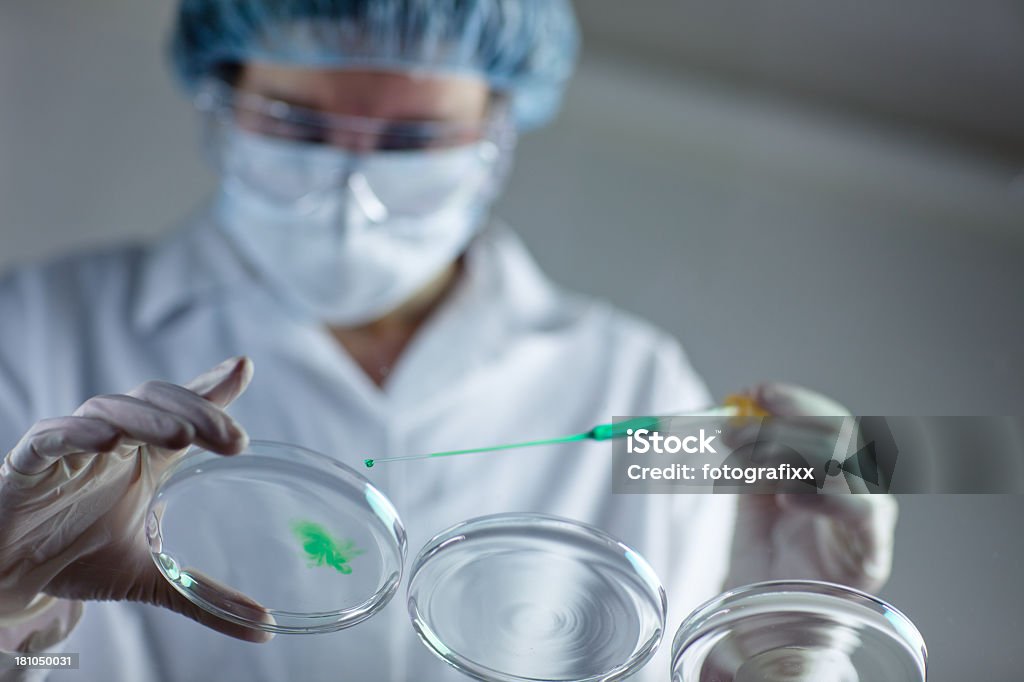 Исследователь и защитные перчатки работает с пипетки и зеленый жидкий - Стоковые фото Бактерия роялти-фри