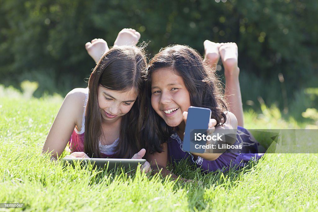 Niñas jugando con reproductor de MP3 y tableta Digital - Foto de stock de Acostado libre de derechos