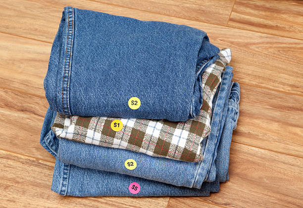 Price stickers on this pile of folded jeans show how cheap you can pick up second hand clothing at yard sales or garage sales.