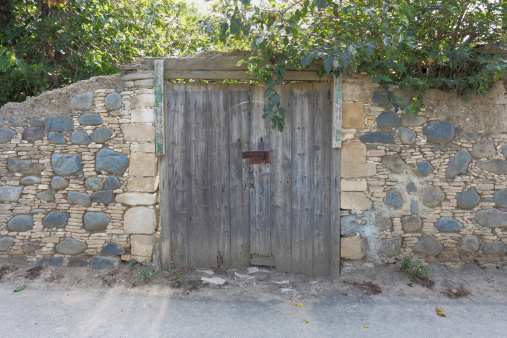 backlit grey  brown  wooden door in rustic village wall  Cyprus