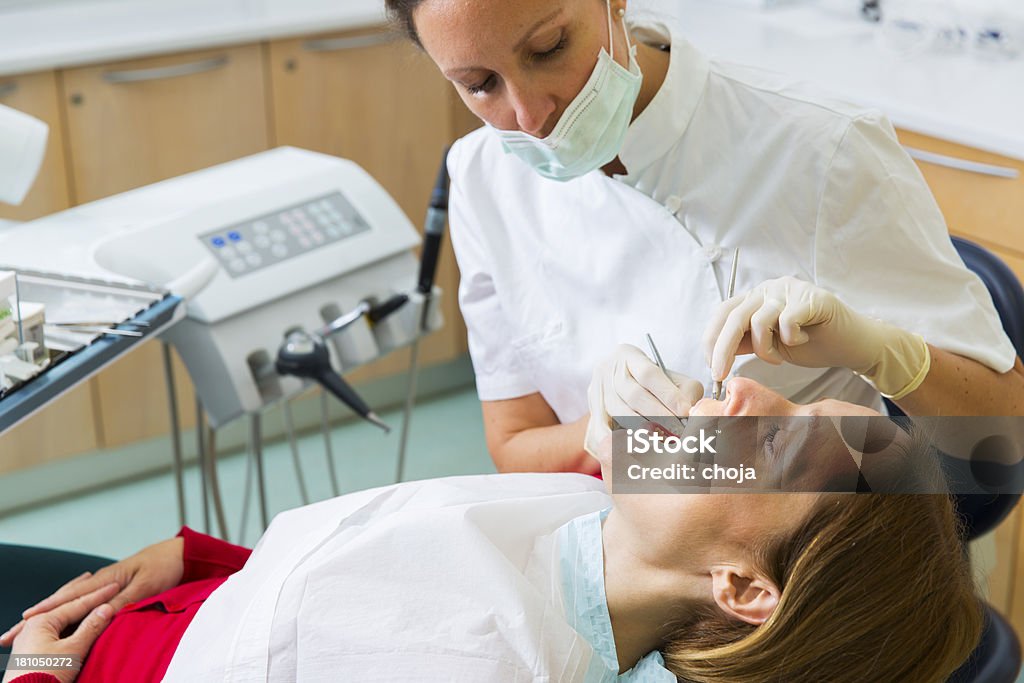 Dentista femmina in ufficio con donna paziente sulla sedia dentisti - Foto stock royalty-free di Adulto