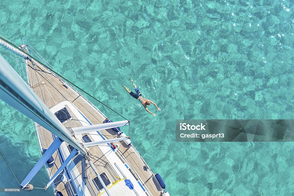 summer vacation man swimming next to a sailing yacht in a turquoise water, high angle view Yacht Stock Photo
