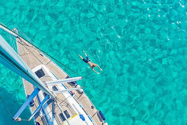 summer vacation man swimming next to a sailing yacht in a turquoise water, high angle view anchored photos stock pictures, royalty-free photos & images