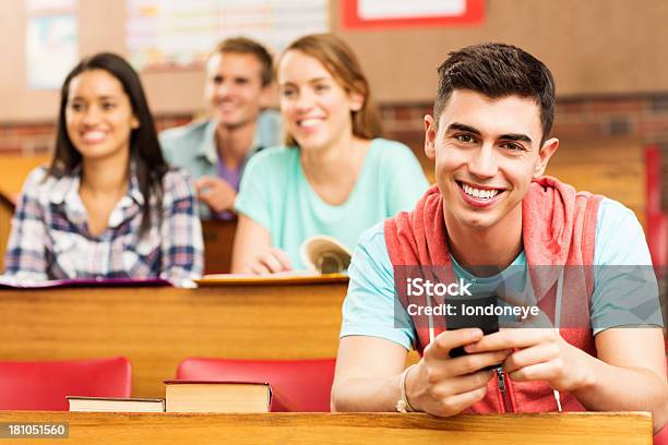 Foto de Estudante Do Sexo Masculino Com Telefone Inteligente Sentado Na Mesa De Sala De Aula e mais fotos de stock de 16-17 Anos