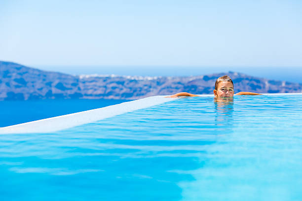 istock Kid in  infinity swimming pool on Santorini, Greece 181051794