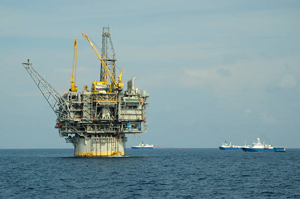 Oil production platform and seismic vessels stock photo