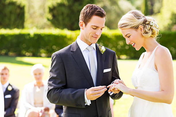 istock Groom Putting Wedding Ring On Bride's Finger During Ceremony 181052814