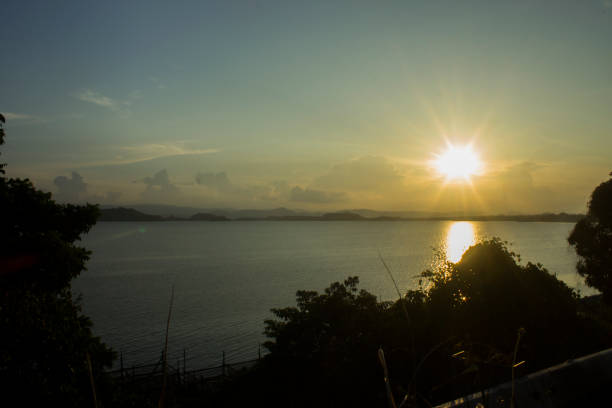 View of the evening sun setting with its golden light reflected on the water of the lake.