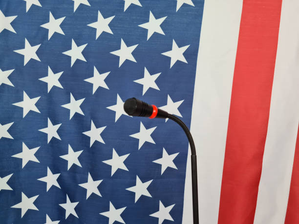 istock Microphone on podium against american flag 1810537521