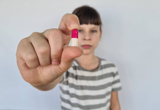 istock Little girl with vitamin tablet on light background 1810537544