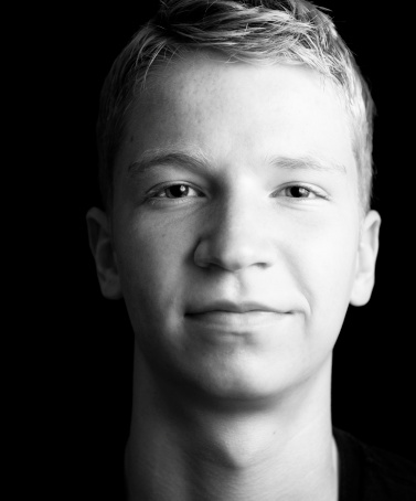 Teenager smiling at camera on a black background.
